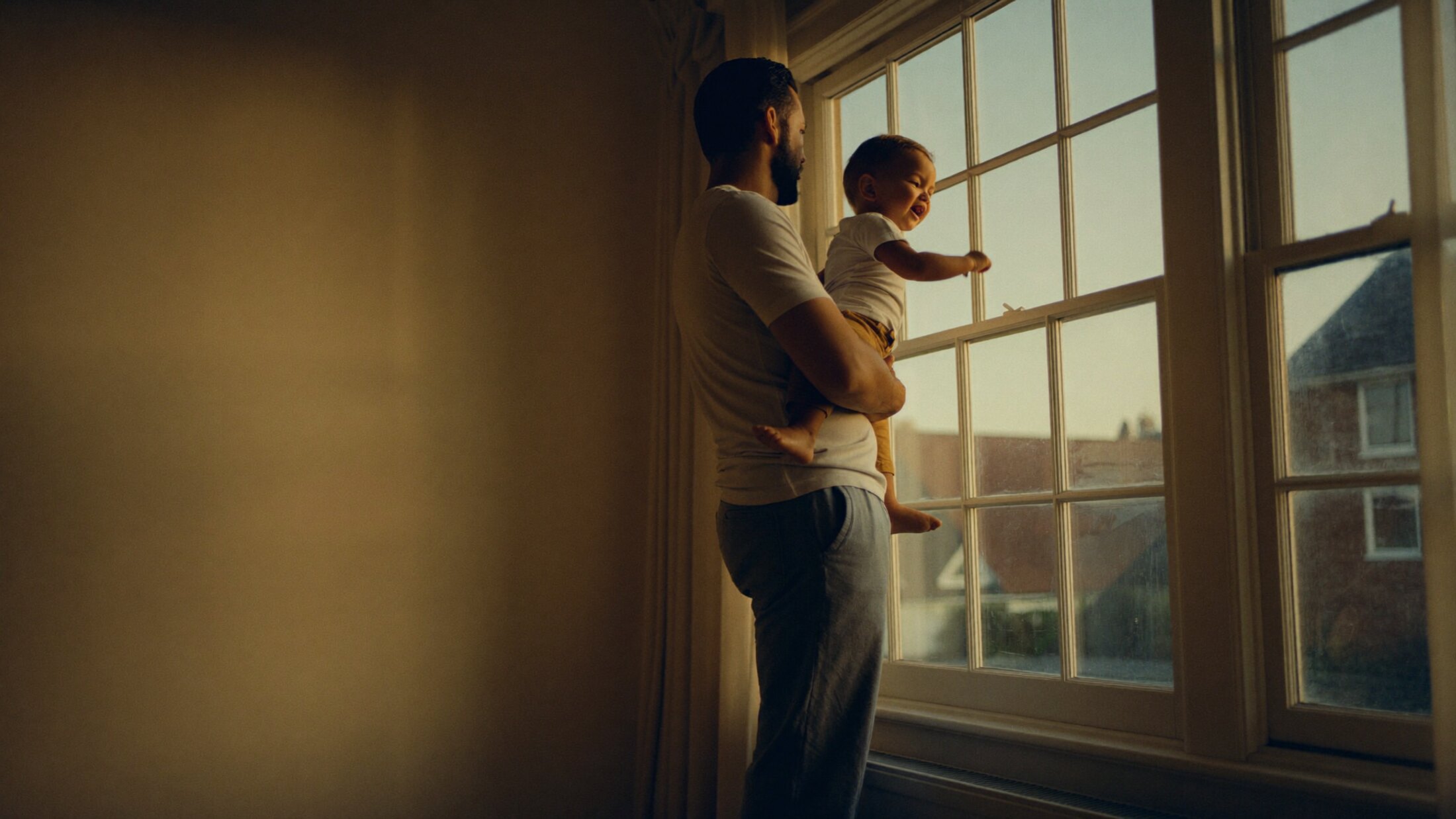 A father holding his child by a window